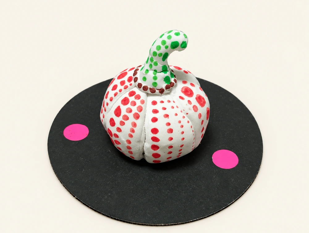 波点南瓜 / Polka-Dot Pumpkin — Red dots cover a white pumpkin, green dots decorate its curved stalk, and bright circles sit on the black round base. Each angle reveals a different pattern.