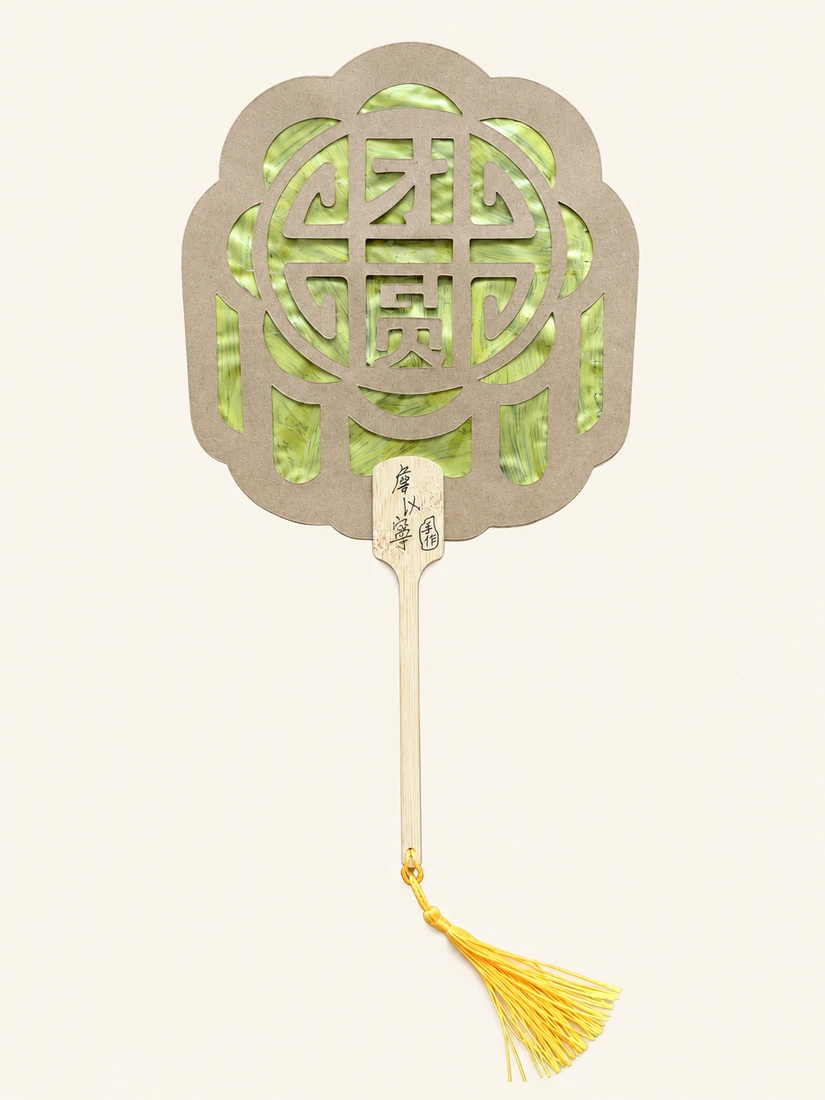 绿色纹理的团圆团扇，木色镂空扇面与长柄，下方垂着黄色流苏。